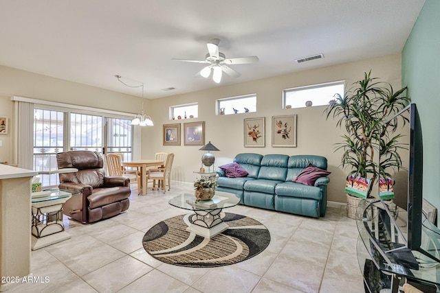 living room featuring light tile patterned flooring, baseboards, visible vents, and ceiling fan with notable chandelier