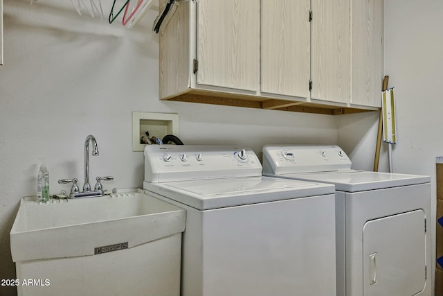 clothes washing area featuring cabinet space, a sink, and washer and clothes dryer