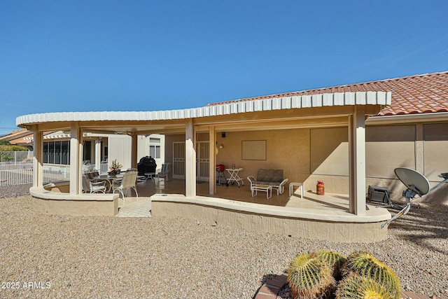 rear view of property with a tile roof, fence, and a patio