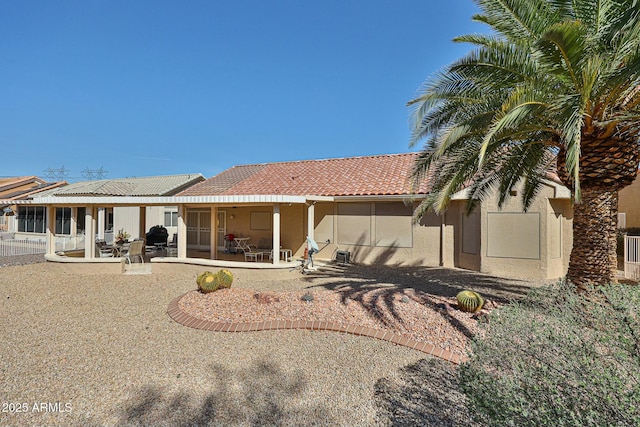 rear view of house featuring a tile roof, a patio, and stucco siding