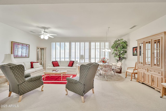 living room with ceiling fan with notable chandelier, visible vents, and light colored carpet