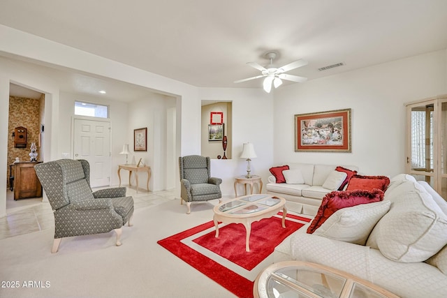 living room with light tile patterned flooring, ceiling fan, visible vents, and light colored carpet