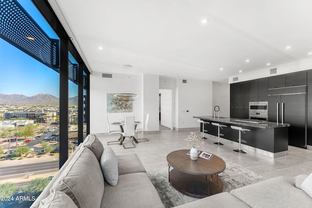 living room featuring a mountain view, floor to ceiling windows, and sink