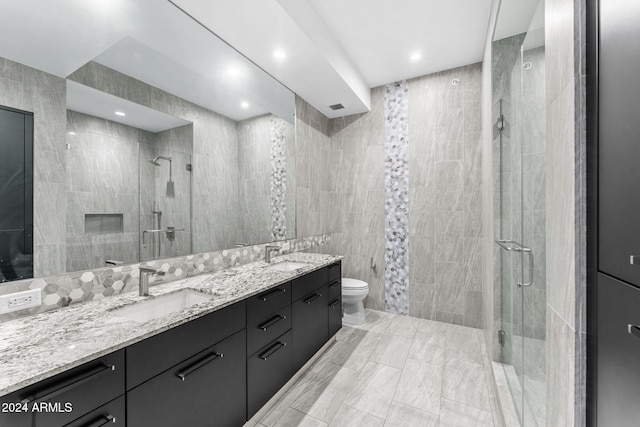 bathroom featuring vanity, toilet, tile walls, and a shower with shower door