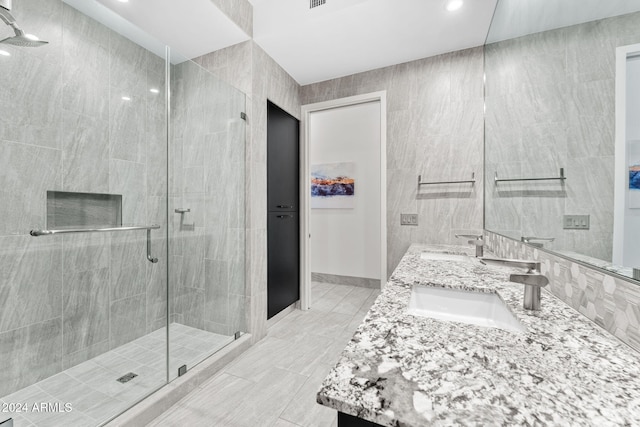 bathroom with vanity, a shower with shower door, and tile walls