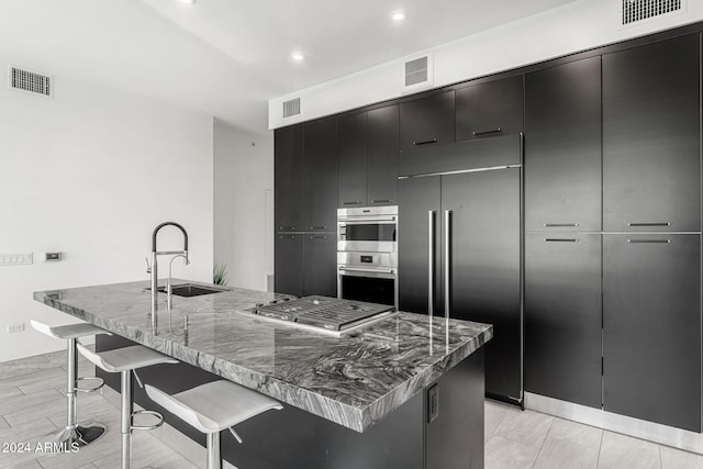 kitchen featuring dark stone counters, sink, a breakfast bar area, a large island, and stainless steel appliances