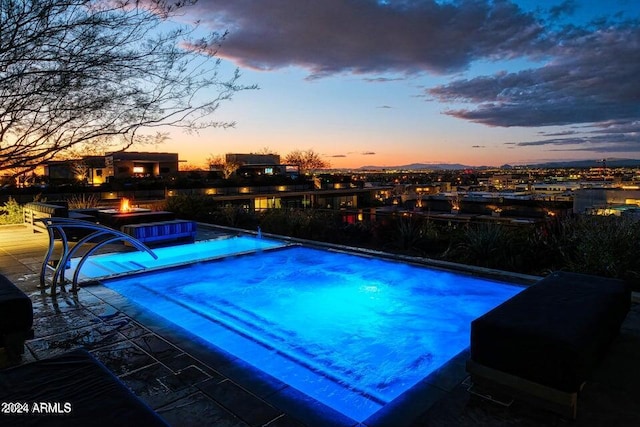 pool at dusk with a fire pit, a jacuzzi, and a patio