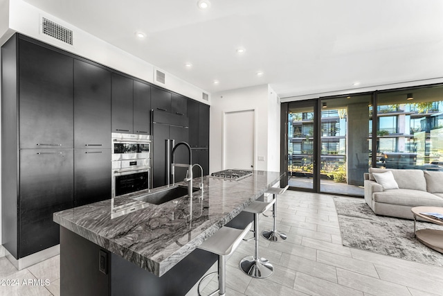 kitchen featuring floor to ceiling windows, a kitchen breakfast bar, sink, appliances with stainless steel finishes, and a large island