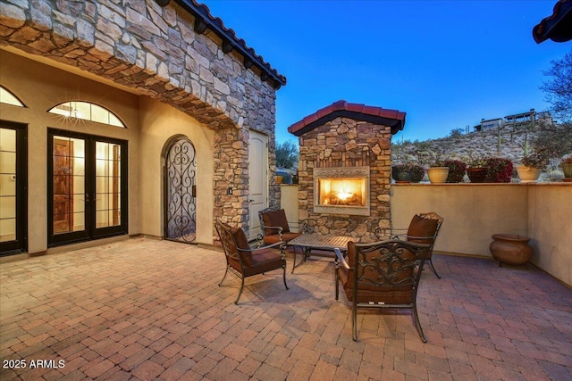 view of patio with french doors and an outdoor stone fireplace