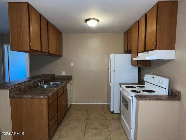 kitchen featuring sink, light tile patterned floors, and white appliances