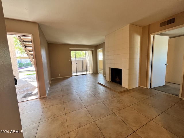 unfurnished living room with a tiled fireplace and light tile patterned floors