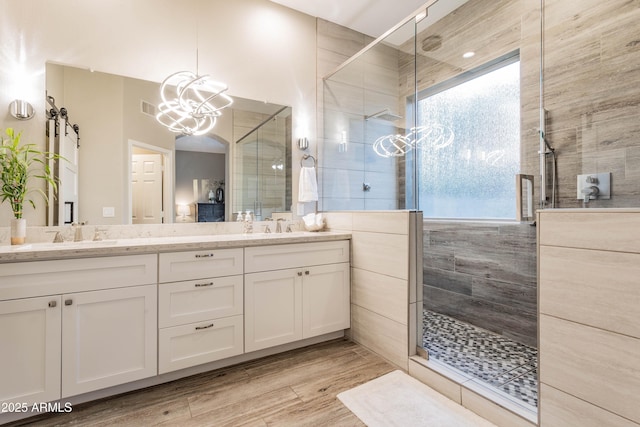 4422 E Spur Dr, Cave Creek, AZ 85331 - bathroom featuring a tile shower, double vanity, wood finished floors, and a chandelier