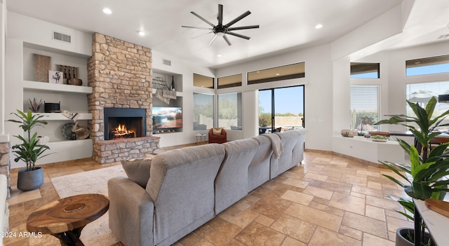 living room with built in shelves, ceiling fan, a fireplace, and a wealth of natural light