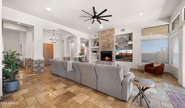 living room with a fireplace, built in shelves, and ceiling fan with notable chandelier