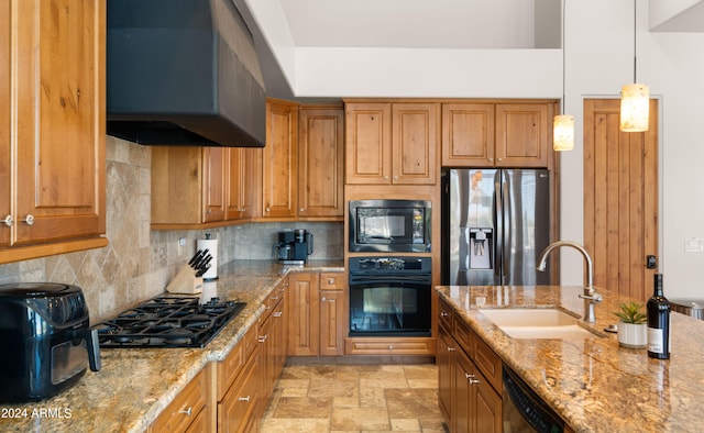 kitchen with black appliances, sink, wall chimney exhaust hood, decorative light fixtures, and light stone counters