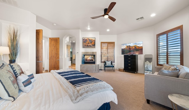 carpeted bedroom featuring a multi sided fireplace and ceiling fan