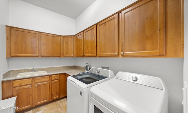 clothes washing area with cabinets, washer and clothes dryer, and sink