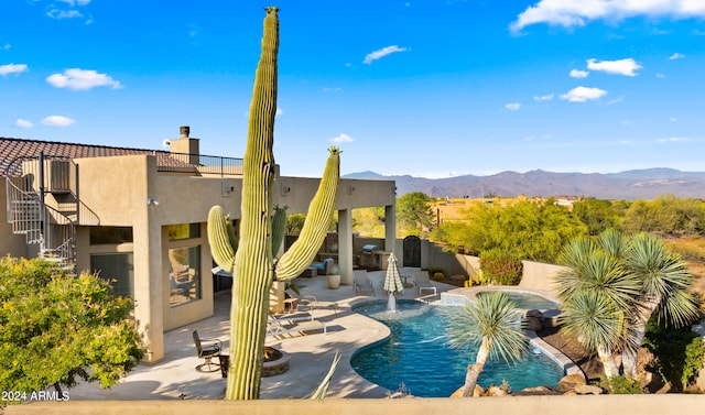 view of pool featuring pool water feature, a mountain view, a patio, and a hot tub