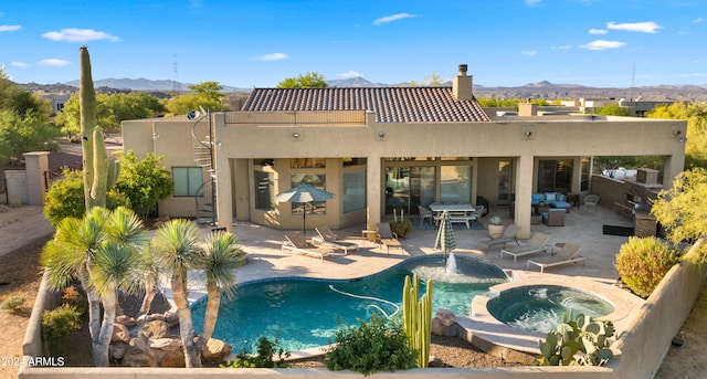 back of property with outdoor lounge area, a mountain view, a swimming pool with hot tub, and a patio area