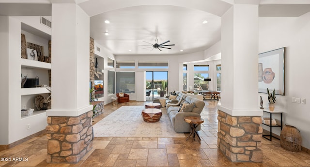 living room featuring ceiling fan, built in features, and a towering ceiling