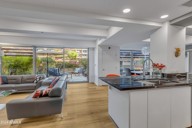 kitchen featuring sink, white cabinets, kitchen peninsula, and light wood-type flooring