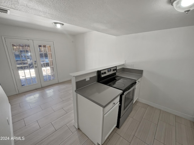 kitchen with stainless steel electric range, french doors, a textured ceiling, white cabinetry, and kitchen peninsula