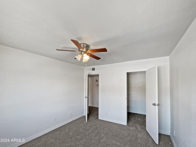 unfurnished bedroom with dark colored carpet, ceiling fan, and a closet