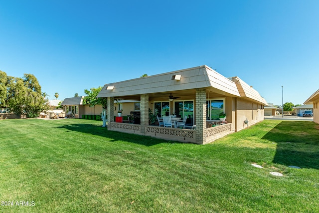 rear view of property with a yard and ceiling fan