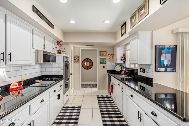 kitchen with stainless steel appliances, backsplash, sink, light tile patterned floors, and white cabinets