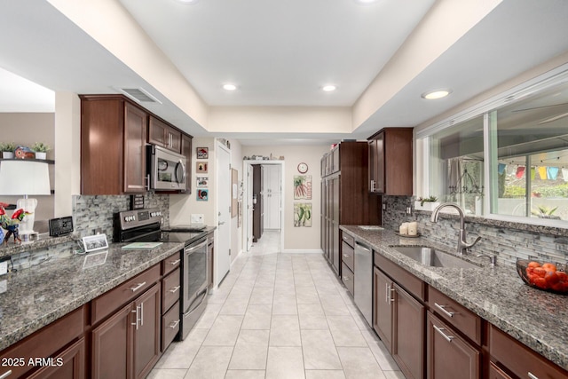 kitchen featuring visible vents, backsplash, dark stone countertops, appliances with stainless steel finishes, and a sink