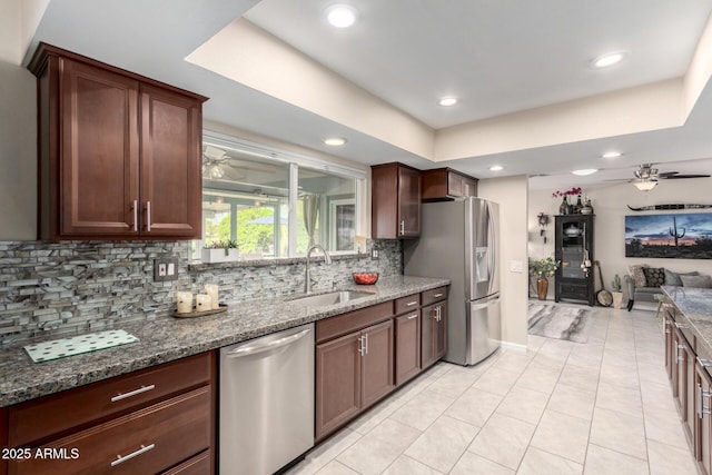 kitchen featuring ceiling fan, a sink, backsplash, and stainless steel appliances