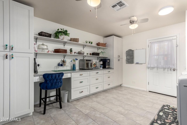 office area featuring built in desk, visible vents, baseboards, and a ceiling fan