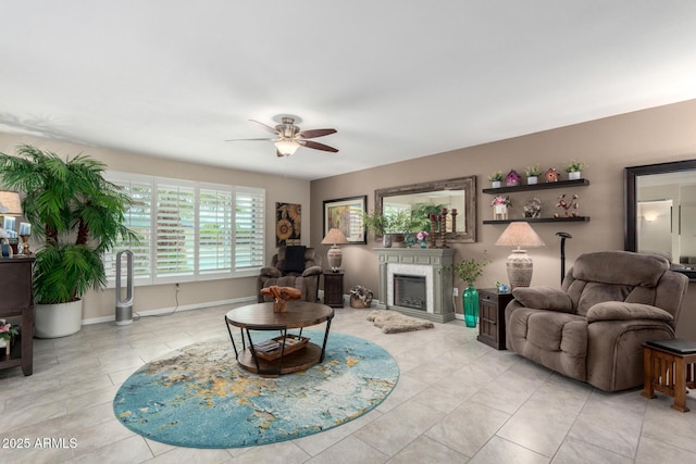 living area featuring baseboards, light tile patterned flooring, a fireplace, and a ceiling fan