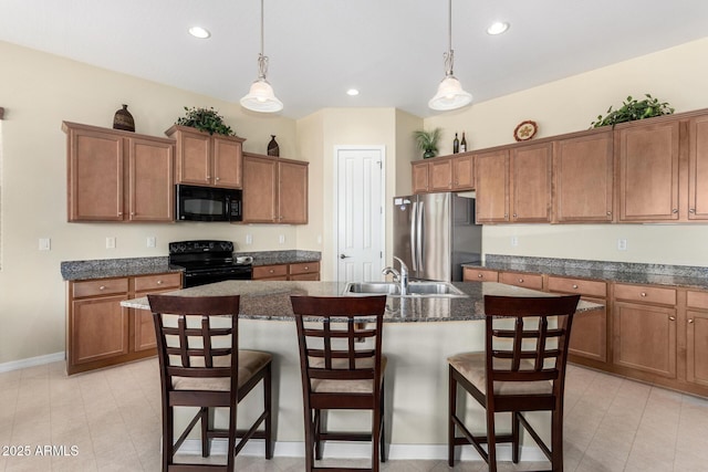 kitchen with an island with sink, sink, a kitchen breakfast bar, and black appliances