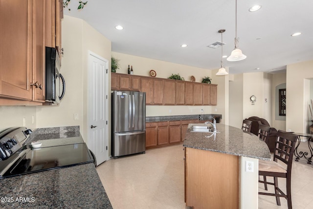 kitchen with sink, a breakfast bar area, appliances with stainless steel finishes, hanging light fixtures, and an island with sink