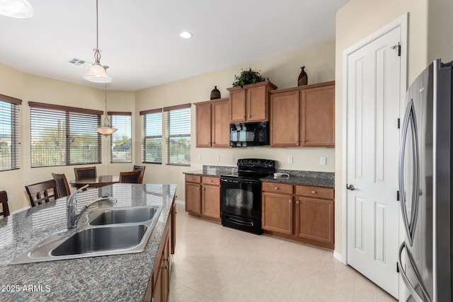 kitchen featuring sink, dark stone countertops, a kitchen bar, hanging light fixtures, and black appliances