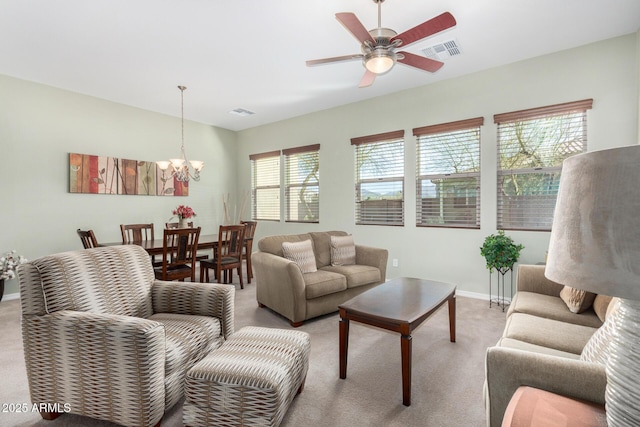 carpeted living room featuring ceiling fan with notable chandelier