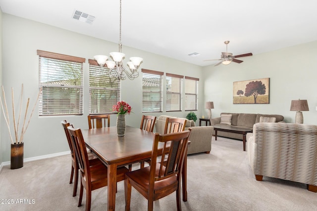 dining area with ceiling fan with notable chandelier and light colored carpet