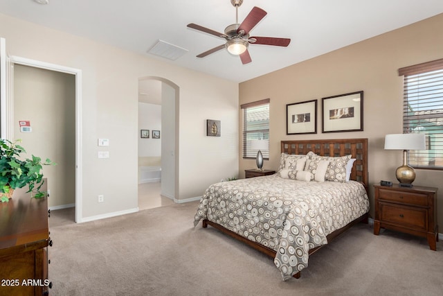 bedroom with light carpet, ensuite bath, and ceiling fan