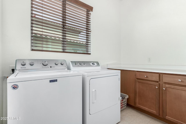 clothes washing area with cabinets and washing machine and clothes dryer