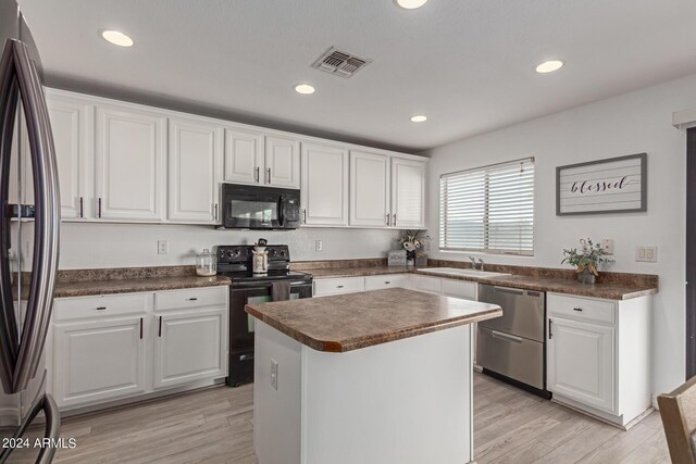 kitchen featuring light wood-type flooring, black appliances, a kitchen island, and white cabinets