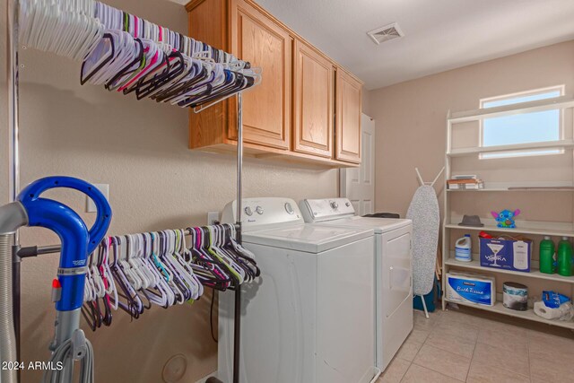 laundry area with cabinets, washer and clothes dryer, and light tile patterned flooring