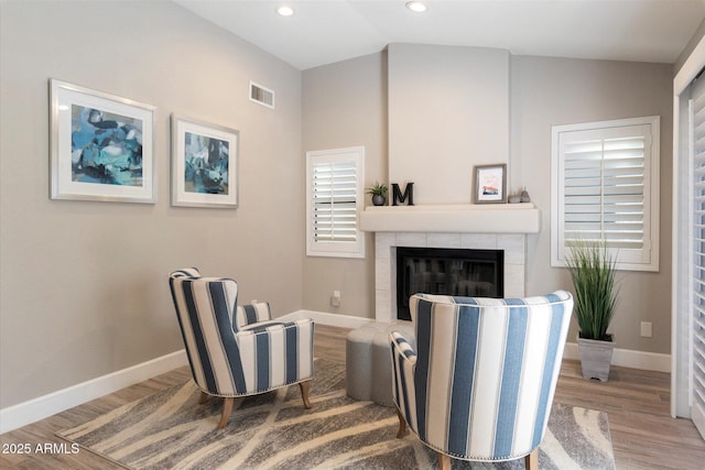 sitting room with a fireplace, light hardwood / wood-style flooring, and vaulted ceiling