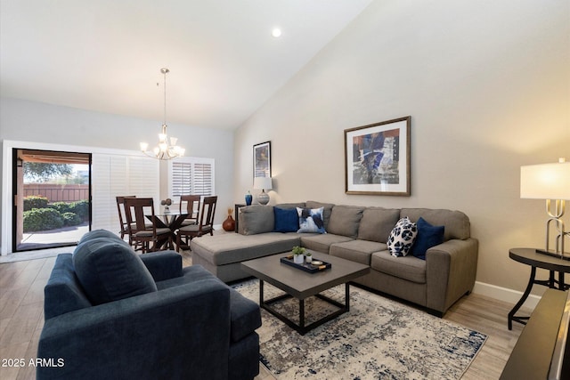 living room with high vaulted ceiling, light hardwood / wood-style floors, and an inviting chandelier