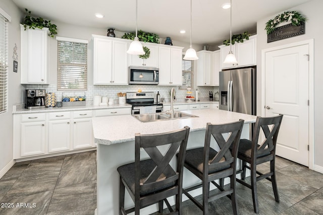 kitchen with stainless steel appliances, a sink, decorative backsplash, a kitchen bar, and recessed lighting