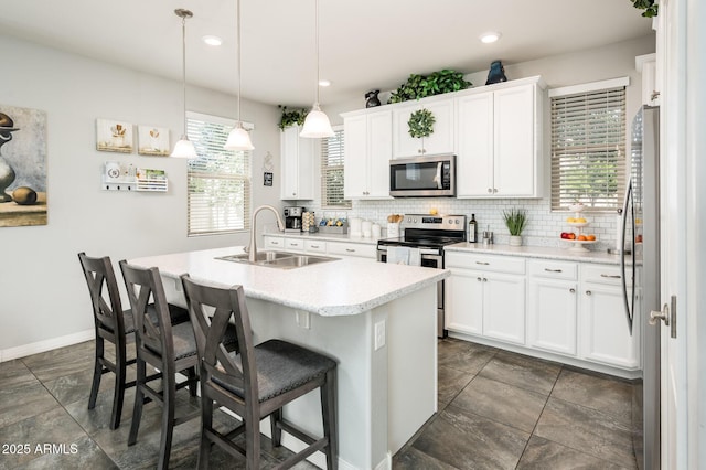 kitchen featuring stainless steel appliances, a sink, decorative backsplash, a kitchen breakfast bar, and an island with sink