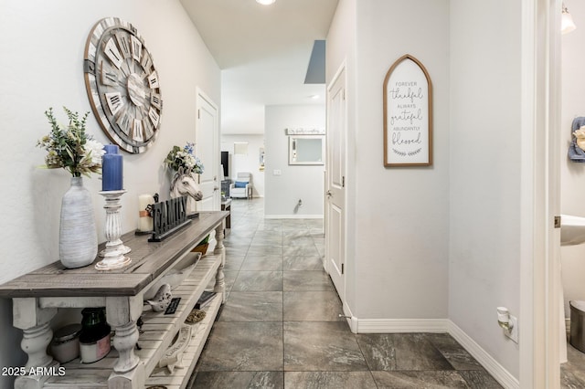 hallway featuring baseboards and stone finish flooring