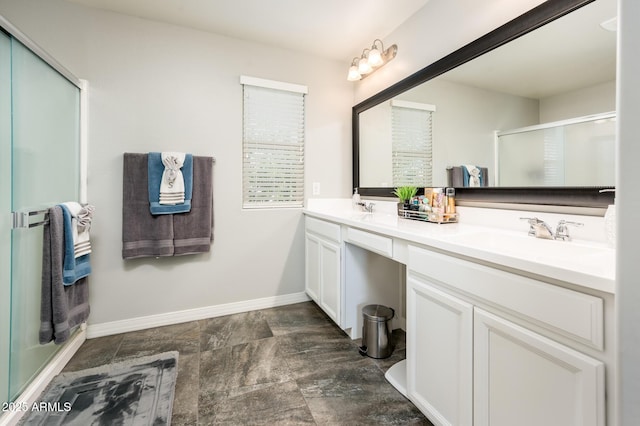 full bath with a stall shower, double vanity, and baseboards