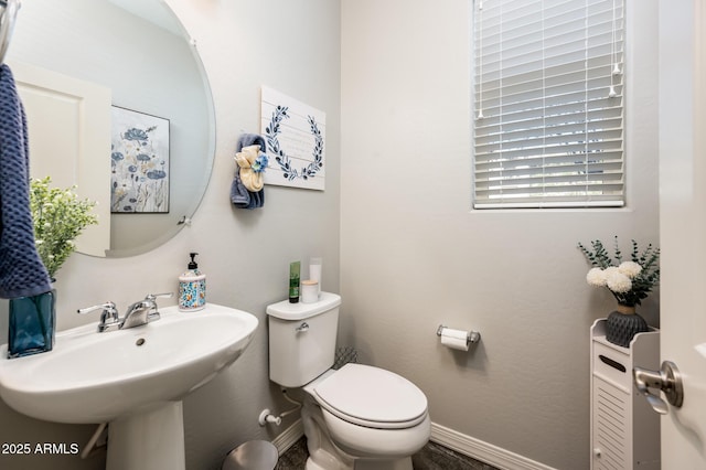 bathroom featuring baseboards, toilet, and a sink