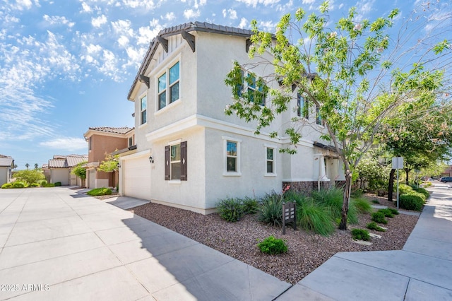 view of property exterior with a garage, stucco siding, driveway, and a tile roof